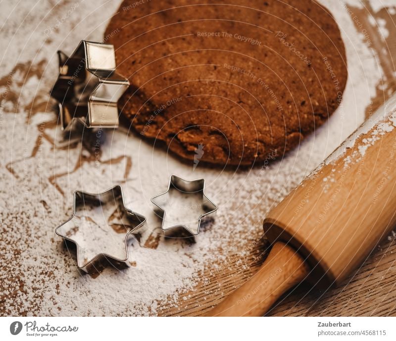 Baking cinnamon stars - dough, cookie cutters on icing sugar, rolling pin behind them in top view Cinnamon Stars Confectioner`s sugar worktop Rolling pin almond