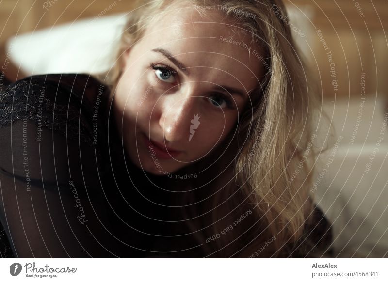 Portrait of a young, blond, long-haired woman lying in bed looking sideways at the camera Youthfulness salubriously Facial expression Warmth inside Lifestyle