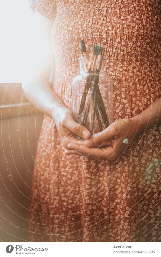 Young woman artist hands grabbing a bottle filled with paint pencils and brushes, ready for painting acrylic. Artistic concepts, artist concept. Beauty dress concept vintage with sun bean