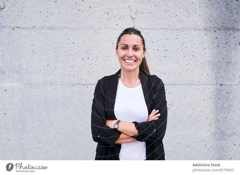 Content brunette standing on street woman delight content smile formal arms crossed wall concrete cheerful lifestyle female entrepreneur employee manager happy