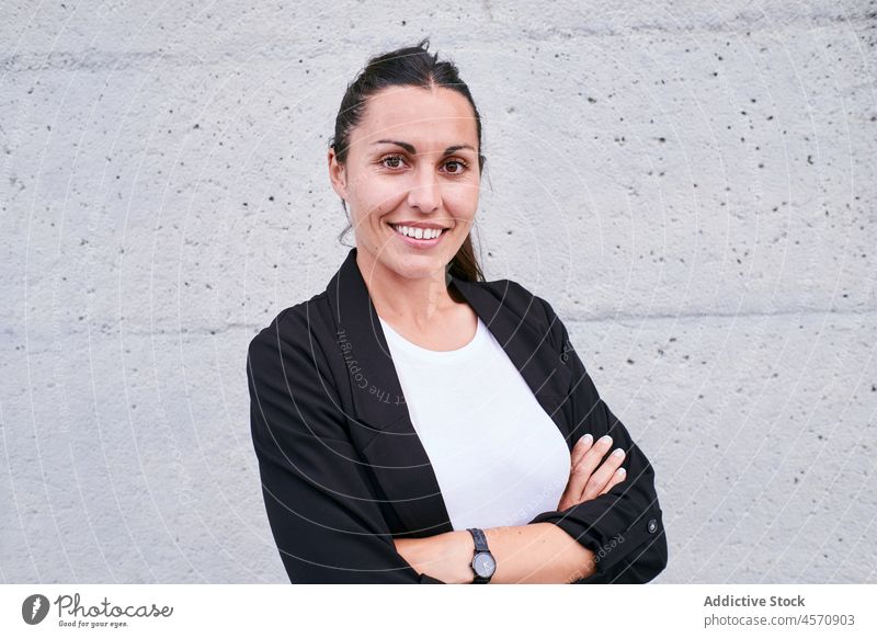 Content brunette standing on street woman delight content smile formal arms crossed wall concrete cheerful lifestyle female entrepreneur employee manager happy