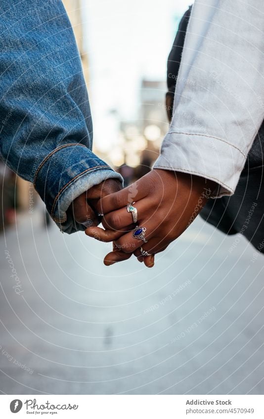 Anonymous ethnic females holding hands during stroll on crowded street women sister friend lgbt couple lesbian together promenade urban city enjoy walk fondness