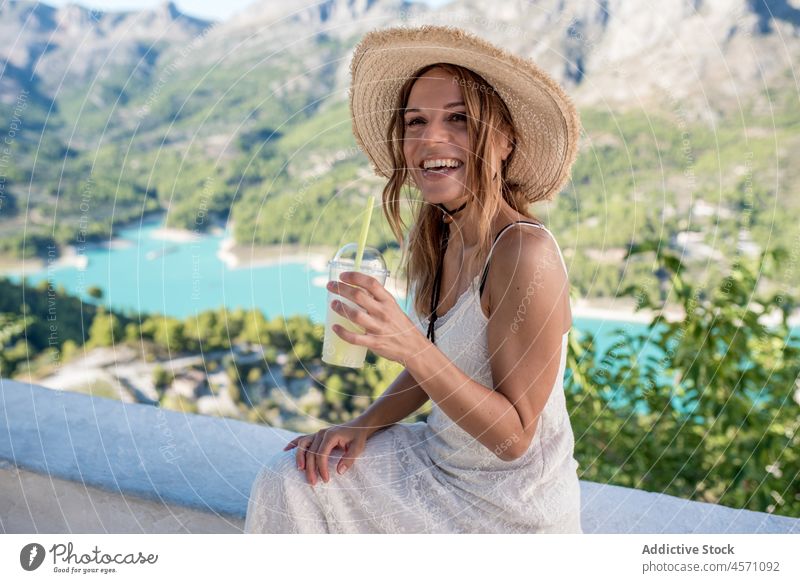 Cheerful traveling woman enjoying refreshing drink in valley traveler mountain lake water beverage refreshment juice recreation nature to go stone shore