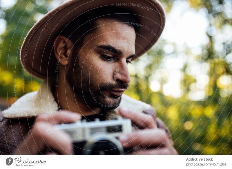 Man standing with vintage photo camera on road man tree path take photo photographer nature grove recreation style portrait adventure trip leisure outfit trendy