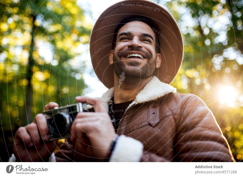 Man standing with vintage photo camera on road man tree path take photo photographer nature grove style portrait adventure trip leisure outfit trendy hat summer