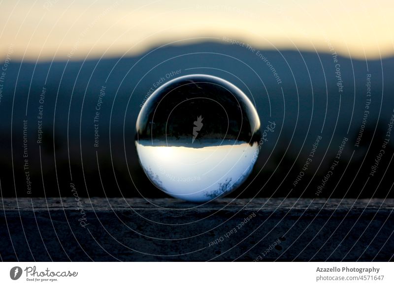 Blurry sinset seen through a lens ball. Lensball with an inverted mountainscape. lensball transparent object landscape nature abstract minimalism beach