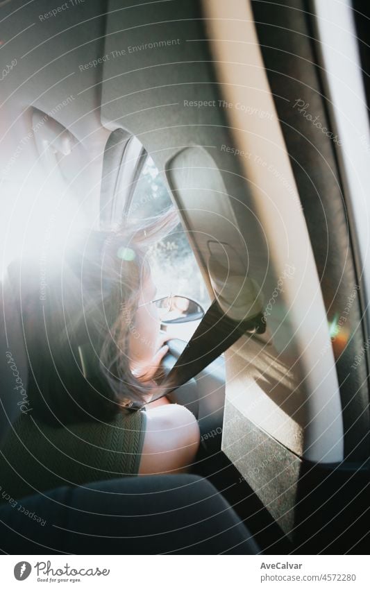 Beautiful Caucasian young hipster female posing during a car trip outside window. Van life lifestyle. Travel and happiness concept. Glasses during a sunset day