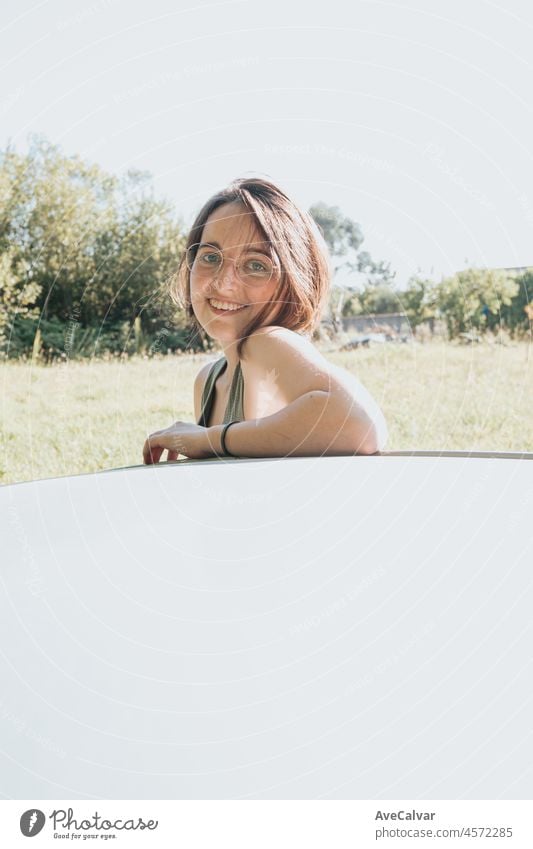 Beautiful Caucasian young hipster female posing during a car trip outside window. Van life lifestyle. Travel and happiness concept. Glasses during a sunset day