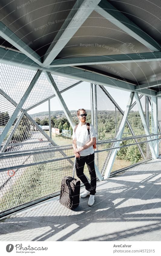 Portrait of a young man at the airport or bus station , luggage, bags and suitcase. Smiling hipster traveler with sunglasses, copy space, sunny day baggage