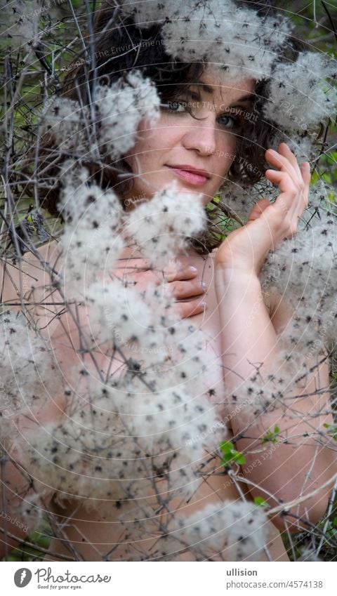 Portrait of a beautiful young sensual brunette woman standing behind clematis vitalba and enjoying her life and nature portrait romantic sexy hidden enjoys