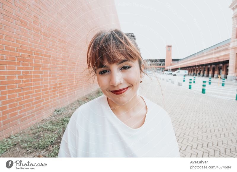 Close up image Outdoor lifestyle portrait of pretty red head young girl, wearing white tshirt and militar boots on urban background. Wearing black jeans denim. Bright day. Happy looking.