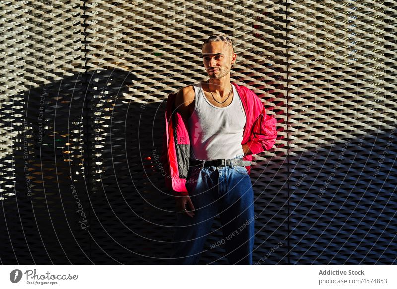 Confident stylish man standing near metal grid eccentric trendy cool personality alternative appearance unusual millennial confident male dyed hair style