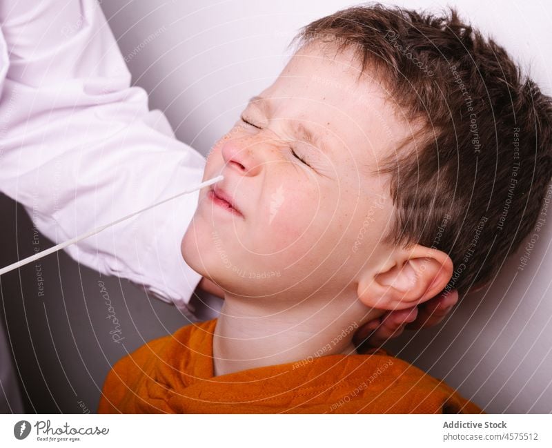 Crop doctor doing swab test to boy patient coronavirus sample hospital pandemic medicine infection kid eyes closed clinic nurse specialist covid 19 uniform