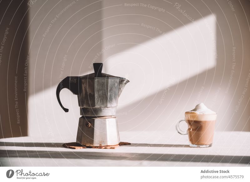 Glass of latte macchiato with moka pot served on table in daylight geyser coffee coffeemaker homemade aromatic beverage delicious drink energy glass brew