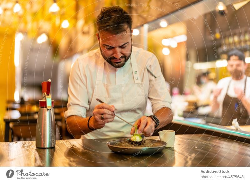 Chef serving plate with sea urchin in haute cuisine restaurant man chef serve gastronomy prepare ingredient gourmet job male cook cream palatable portion