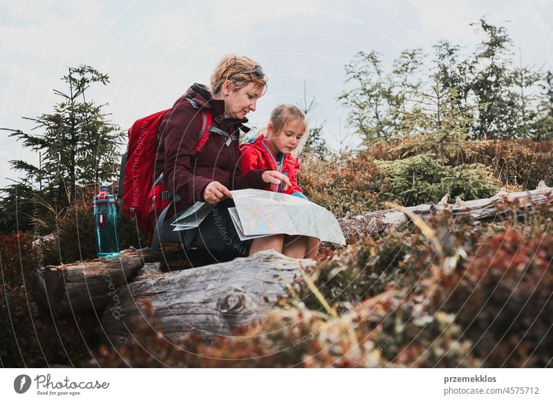 Family trip in mountains. Mother and her little daughter examining a map, sitting on stump during trip family child vacation summer hike travel journey active