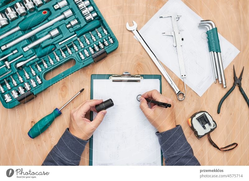 Man working in workshop using many tools. Wrench, spanner, calliper and ratchet with many attachments. Professional equipment repair engineering mechanic