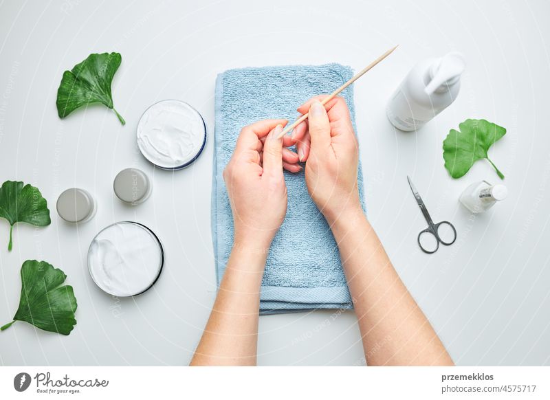 Woman applying  cosmetic moisturizing hand cream. Cosmetic products, green leaves on white table. Spa, manicure, skin care concept nail woman beauty moisturizer