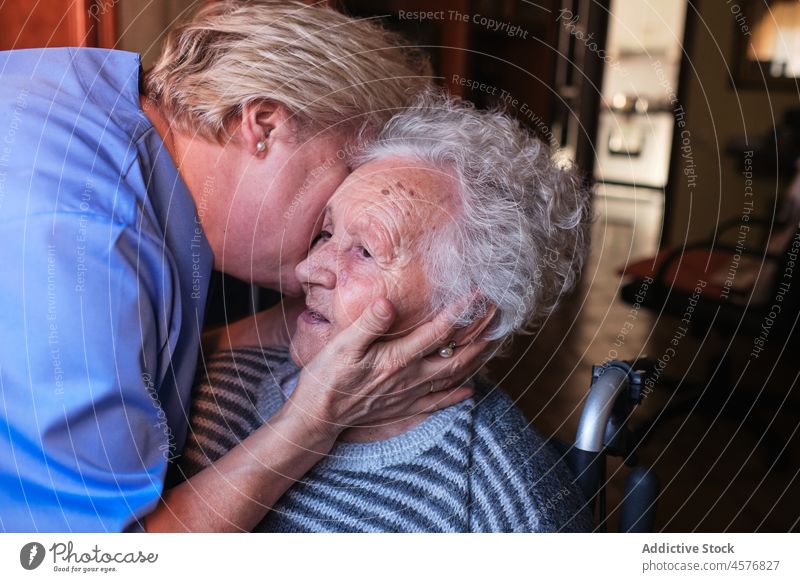 Nurse hugging aged woman in room nurse elderly patient help kiss care love support disable pensioner old specialist affection home apartment retire embrace