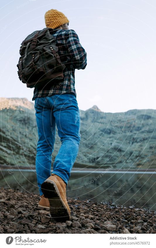 Unrecognizable hiker on shore against mountains man tourist water lake journey waterside nature ridge stone rough formation coast rocky waterfront surface trip