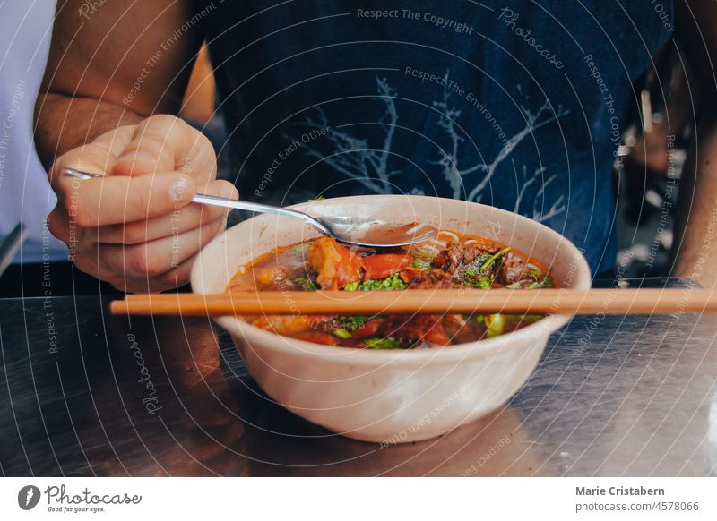 Person eating Vietnamese Fried Fish Vermicelli Noodle Soup (Bun Ca), a traditional food eaten after Tet Holiday for luck bun ca vietnamese food vermicelli soup