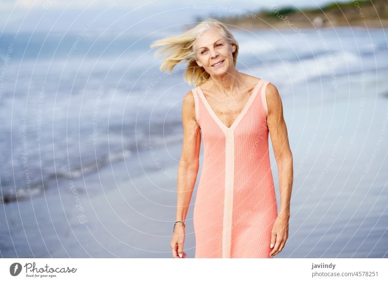 Elderly female enjoying her retirement at a seaside retreat. Senior woman on shore of a beach. mature senior old person lifestyle happy holiday relaxing sand