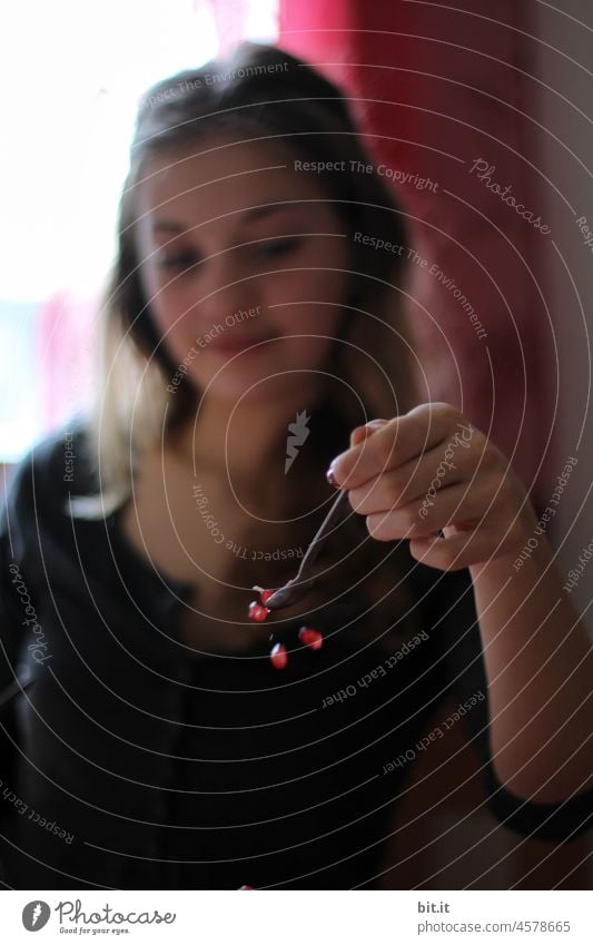 Letting go - young woman holding a spoon from which grains of a pomegranate fall. Young woman Woman portrait Feminine Face Human being pretty