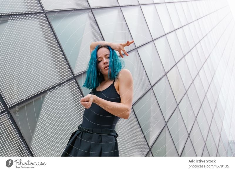 Confident female performing dance near wall of modern building woman hobby choreography portrait charming arms raised dancer appearance trendy style street glad