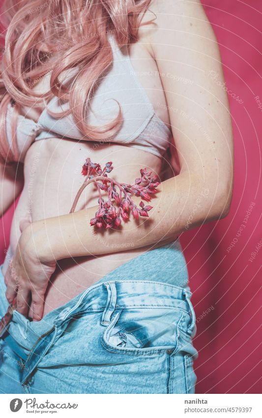 Body image of a real young woman wearing jeans and holding a exotic flower body positive pink femininity female hair bra underwear fashion trendy concept