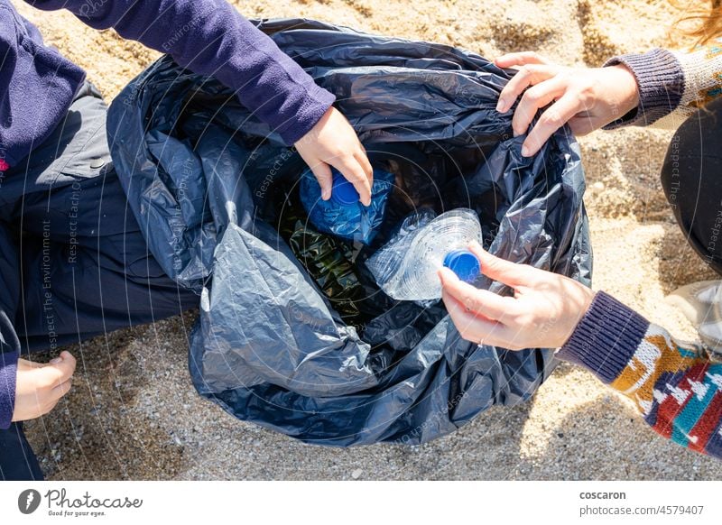 Mother and son picking plastic and garbage on the beach bottle care caucasian child clean cleanup coast collect collecting dirty ecology environment