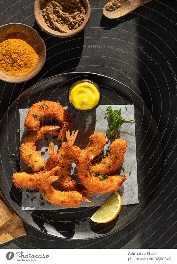 Dish of battered prawns with spices meal snack ingredient delicious tasty sauce roast fish langoustine above hard light lemon black back background table