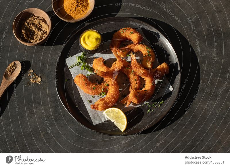 Dish of battered prawns with spices meal snack ingredient delicious tasty sauce roast fish langoustine above hard light lemon black back background table