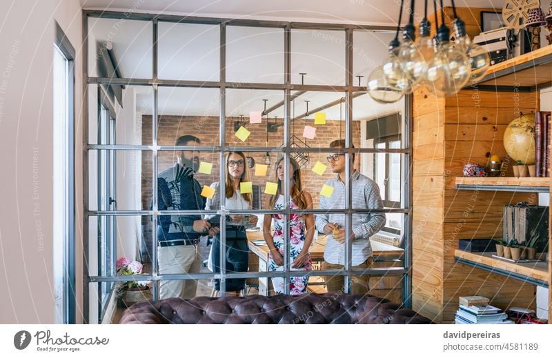 Business people in a work meeting placing sticky notes on the wall worried adhesive notes office glass partition panel through the glass business standing