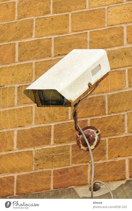 old, defective surveillance camera on a wall of brick tiles / surveillance / dilapidated Surveillance old technology Surveillance camera technique brick wall