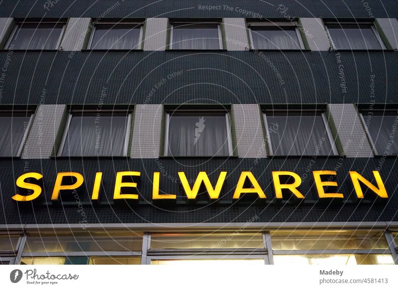 Yellow neon sign on a traditional shop for toys in a typical post-war building in the evening in the Bornheim district of Frankfurt am Main in the German state of Hesse