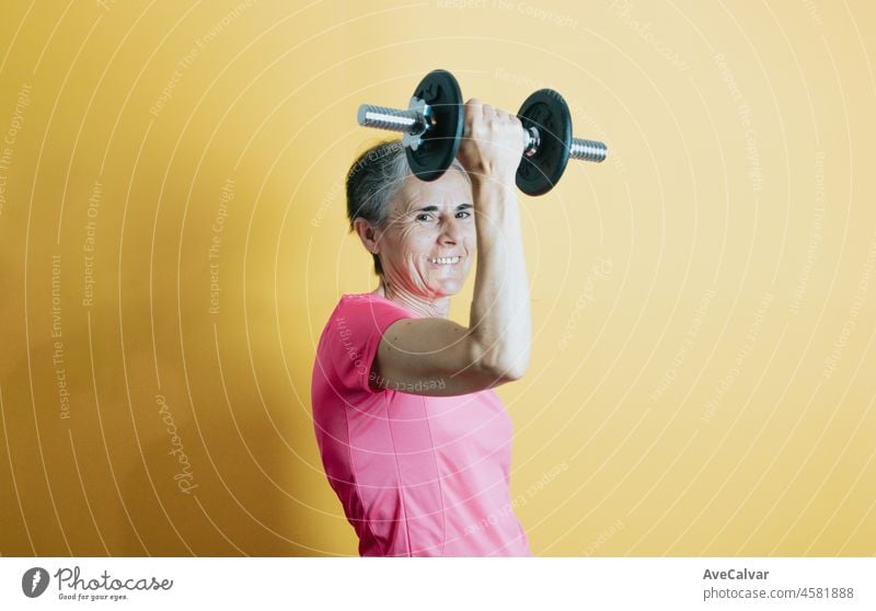 Old senior white hair woman holding a lift with a colourful background. Fitness old people senior concept. Healthy life styles on senior woman to fight the arthritis