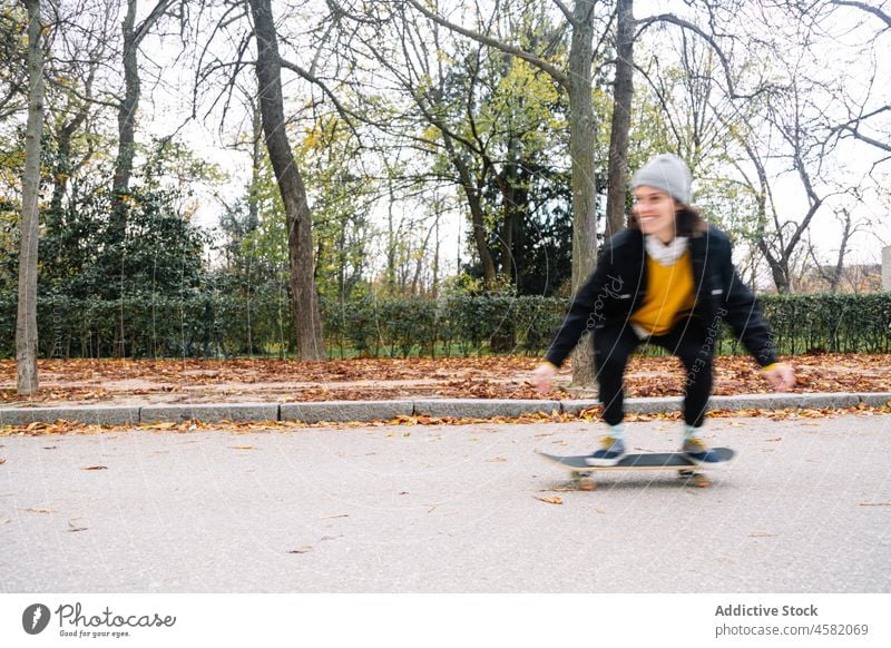 Young female skater riding skateboard in autumn park woman ride cheerful hobby defocused happy road asphalt casual young nature energy activity longboard smile