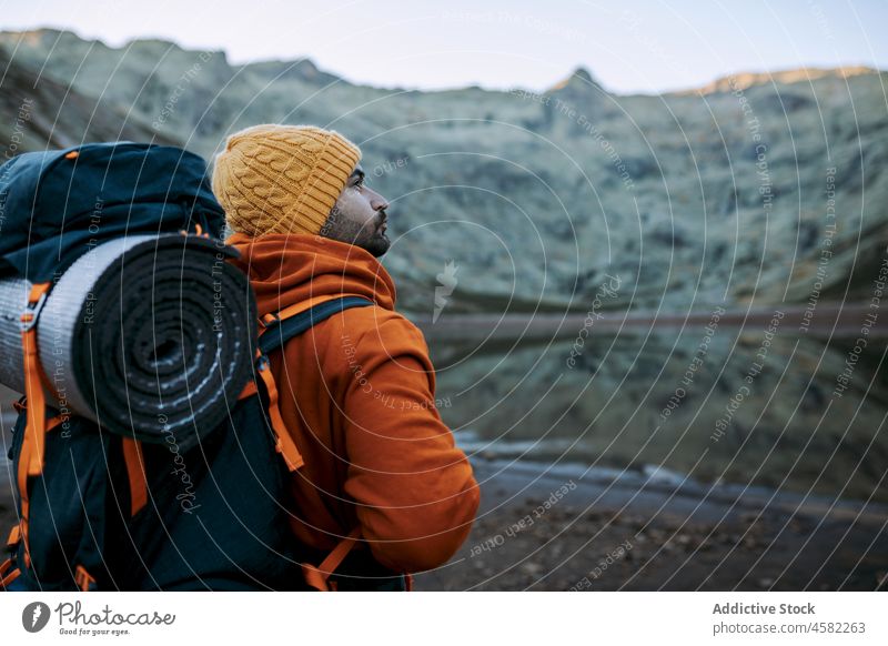 Hiker standing near calm lake man hiker water nature trip trekking backpacker mountain rock explorer travel journey activity natural rural terrain recreation