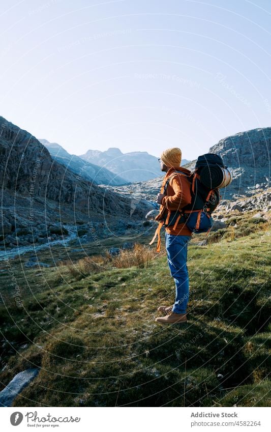 Unrecognizable hiker in mountainous area man traveler nature trip trekking rock explorer hat journey grassy activity active natural rural terrain recreation