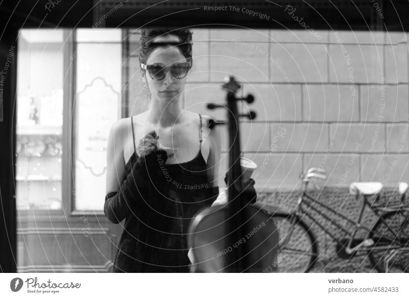 portrait of a cheerful young elegant caucasian woman wearing a tube black dress , having a croissant and a coffee for breakfast in a violin shop, vintage classic elegance concept