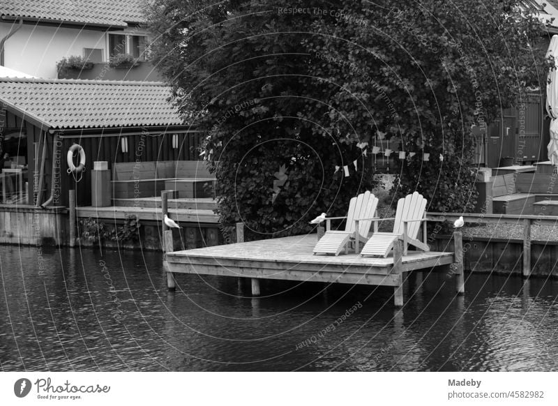 Beautiful wooden deck chairs on an old wooden jetty at the harbour in Steinhude at the Steinhuder Meer near Wunstorf in the district of Hannover, photographed in neo-realistic black and white