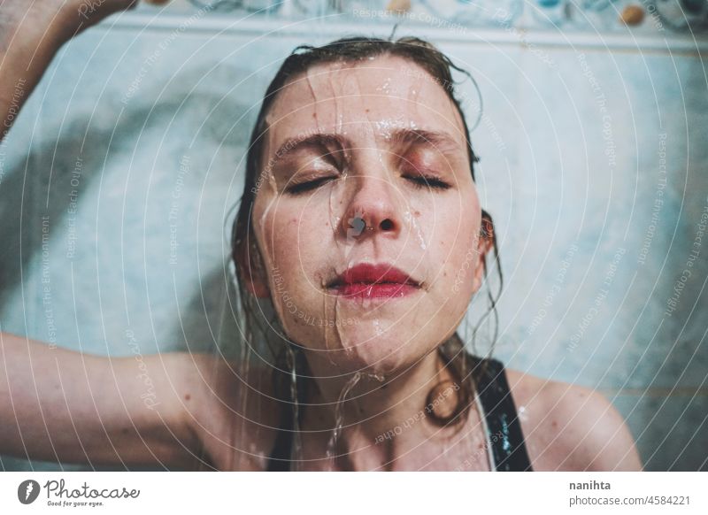 Artistic portrait of a young woman under shower water attractive fresh art artist face wet close natural real pretty long hair sensual sexy make up bath