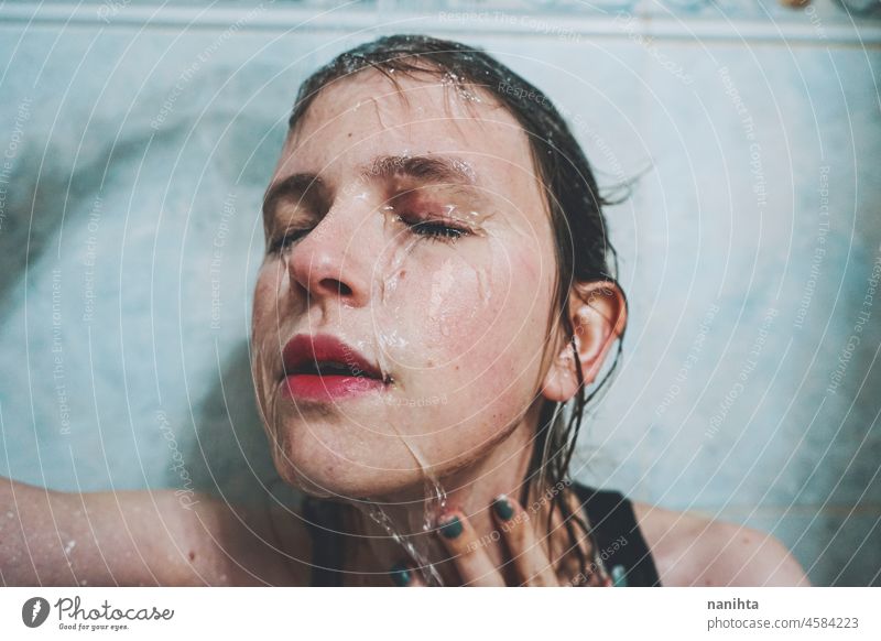 Artistic portrait of a young woman under shower water attractive fresh art artist face wet close natural real pretty long hair sensual sexy make up bath