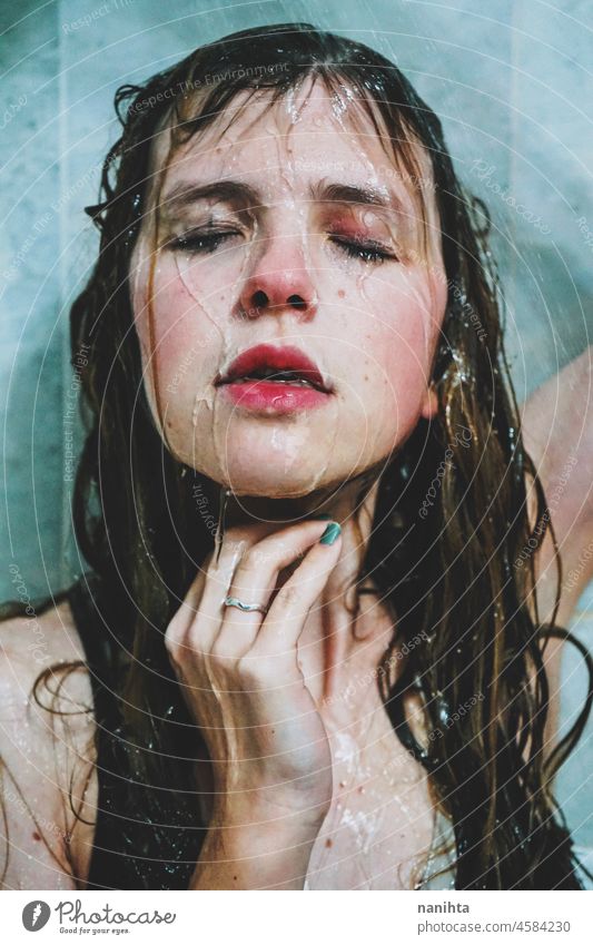 Artistic portrait of a young woman under shower water attractive fresh art artist face wet close natural real pretty long hair sensual sexy make up bath