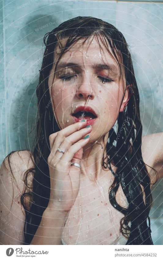 Artistic portrait of a young woman under shower water attractive fresh art artist face wet close natural real pretty long hair sensual sexy make up bath