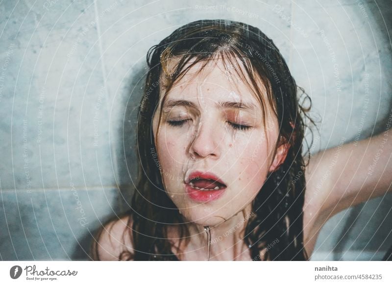 Artistic portrait of a young woman under shower water attractive fresh art artist face wet close natural real pretty long hair sensual sexy make up bath