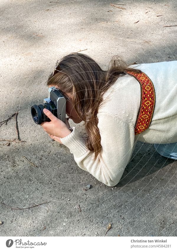 A young woman kneels on the sidewalk and takes pictures with an old analog camera photographer Young woman Take a photo vintage old camera off Sunlight Camera