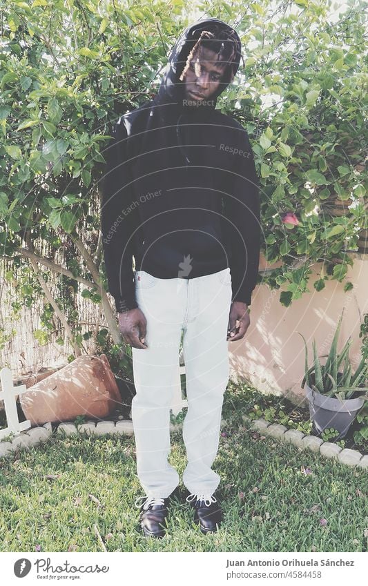 Young black man posing in a garden young african plant grass fashion fashionabe urban style bizarre guy serious person people lifestyle unemotional