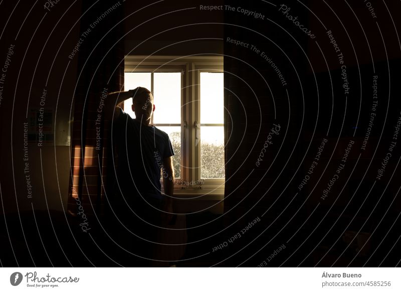 A man, middle-aged, adult, waits for the results of a covid-19 pcr test, self isolate, in a hotel room near Manchester airport, UK young Caucasian window rain