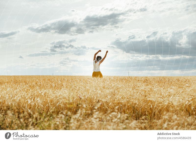 Anonymous woman standing in wheat field nature countryside summer rural skirt natural plantation female brunette calm sky cloudy peaceful meadow lady short hair